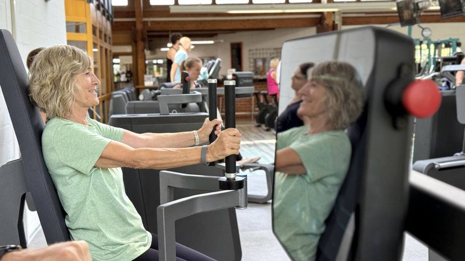 Mitglied trainiert lächelnd an einem Gerät des milon-Zirkels