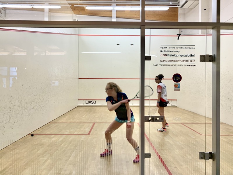 Spielerin holt auf dem Squash-Court zum Schlag aus